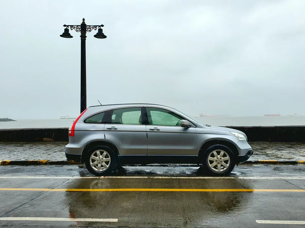 Honda CR-V gris vu de profil sur une route mouillée