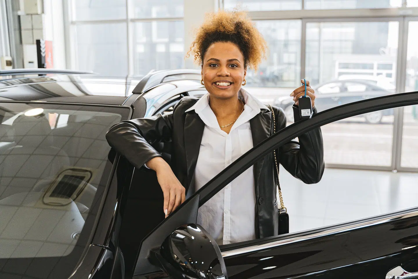 Acheteuse prenant possession d’une voiture dans un espace de vente automobile